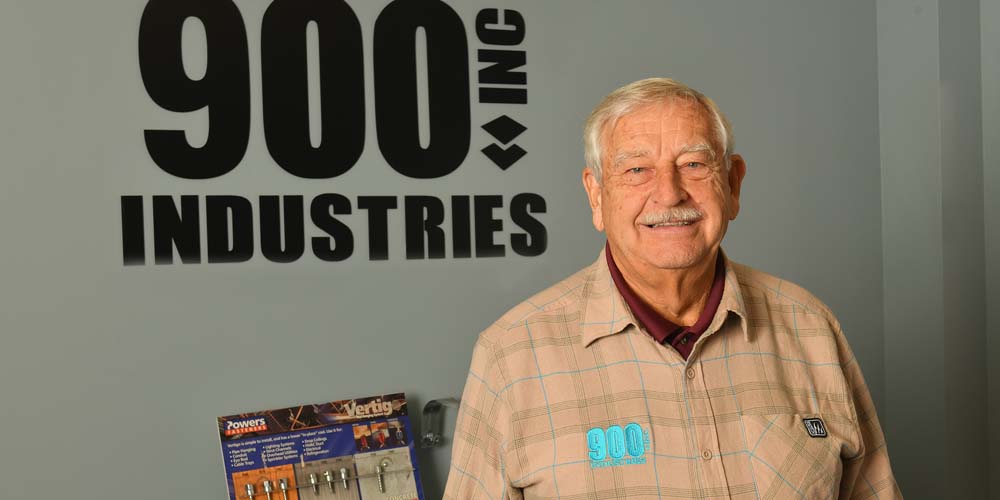 Paul McNamara stands in front of an older 900 Industries logo in the office.